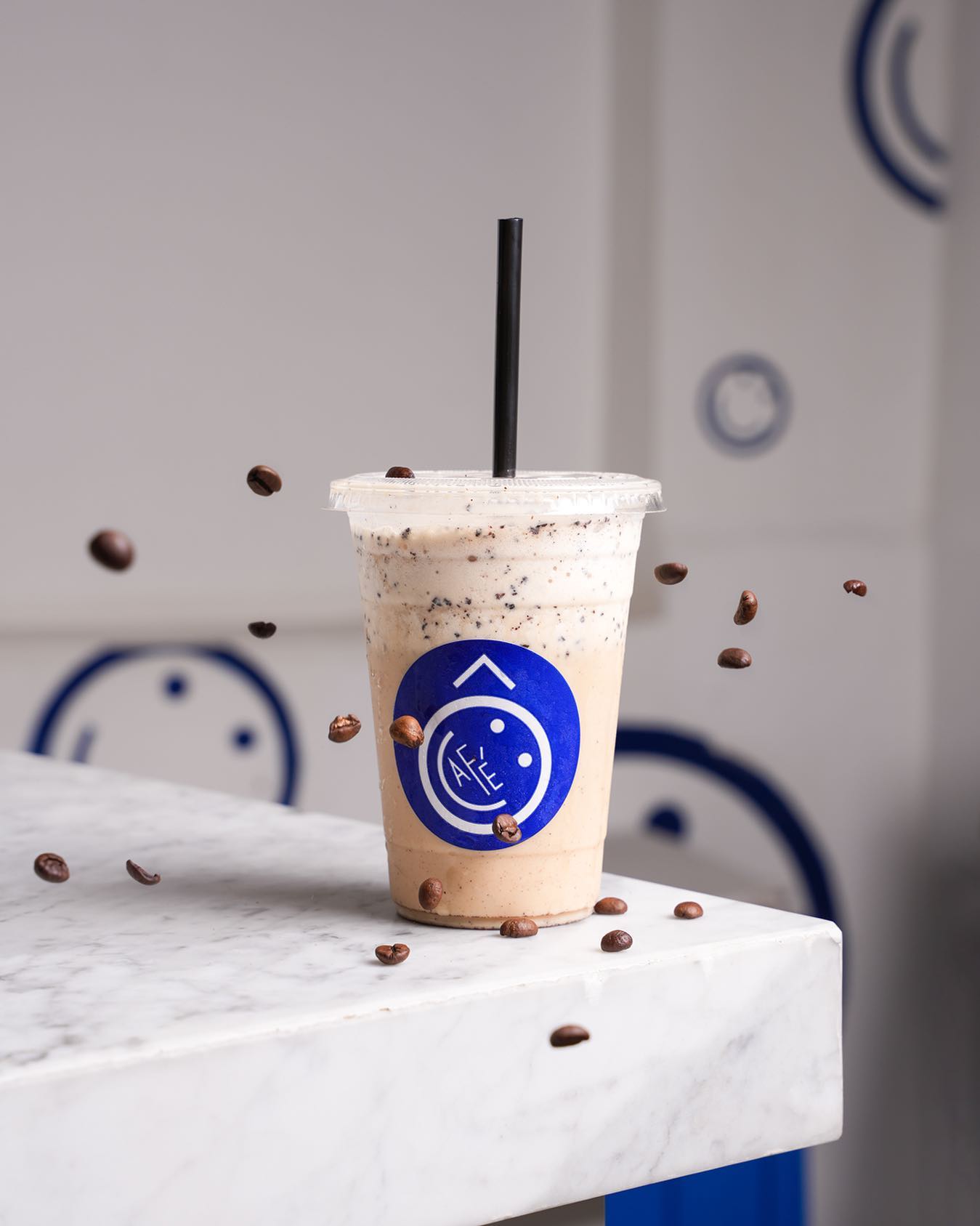 Ô café blended iced coffee on a marble counter with coffee beans suspended mid-air