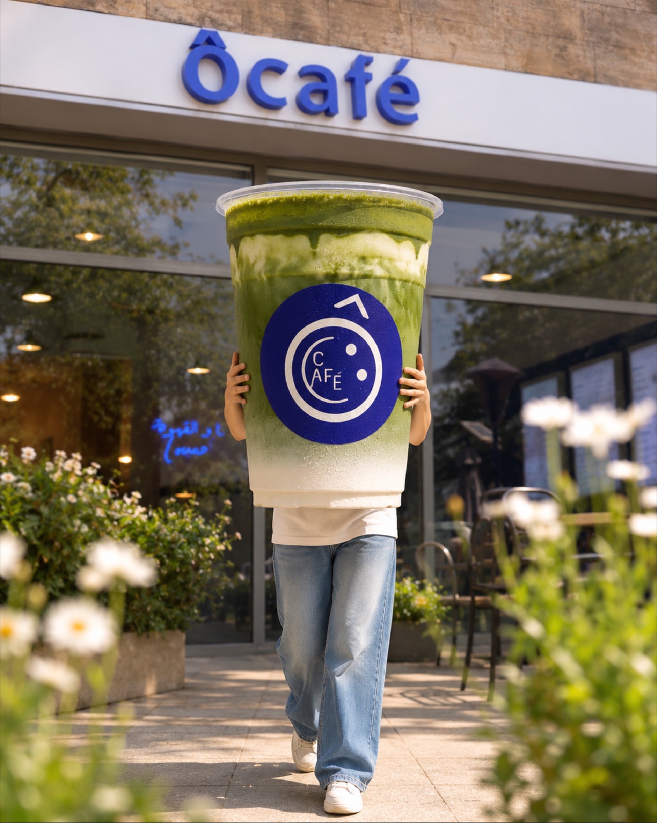 A giant iced matcha cup with the cobalt Ô café logo in front of the Beirut storefront